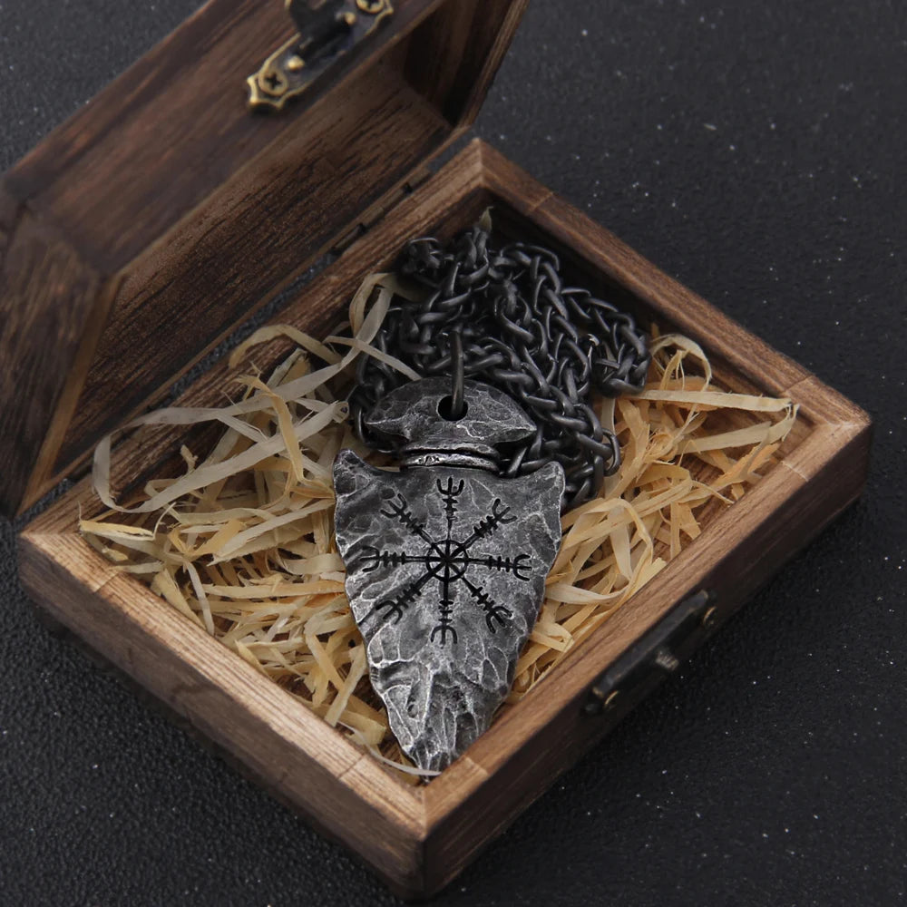 Celtic warrior arrowhead pendant in a wooden box with straw, featuring intricate designs on a black chain.