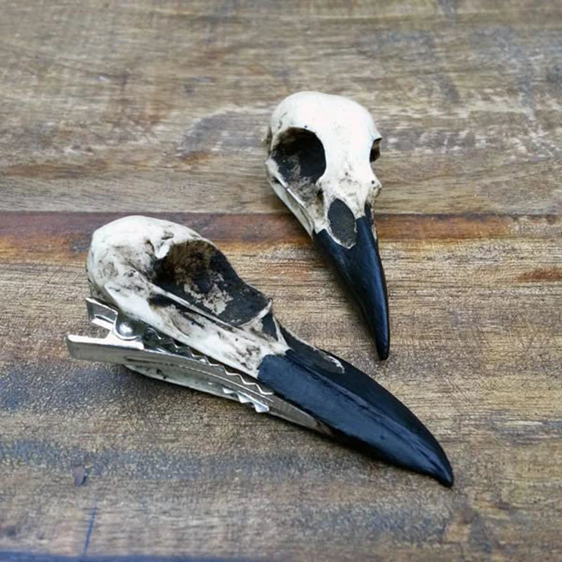 Épingle à cheveux corbeau avec détails de crâne noir et blanc sur un fond en bois.