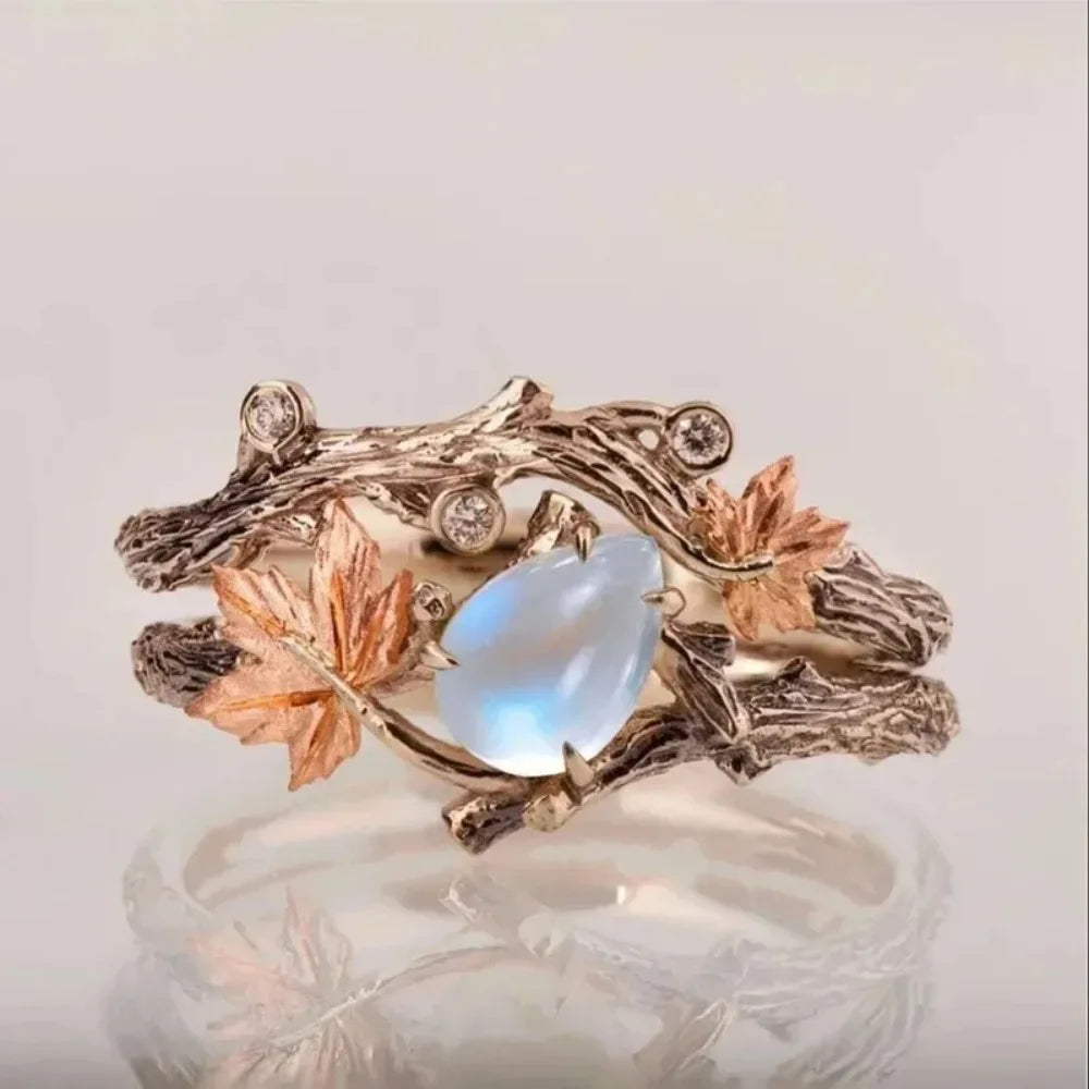 Bague branche d'arbre avec sa pierre blanches, ornée de feuilles délicates et d'une pierre bleue, design naturel et élégant.
