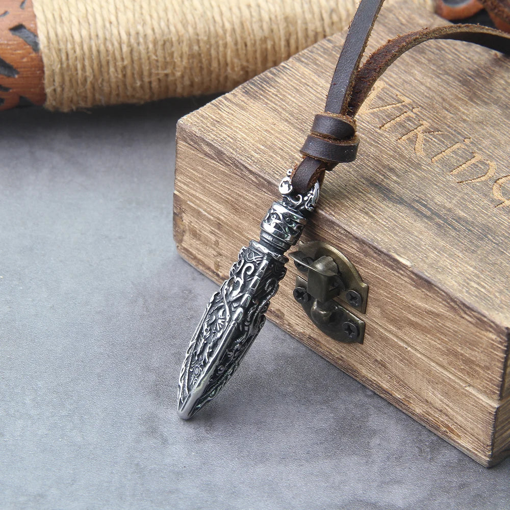 Celtic warrior arrowhead pendant on brown leather cord with ornate details against a wooden box background.