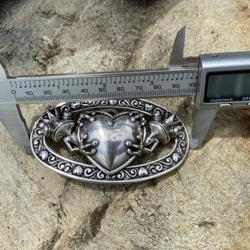 boucle de ceinture celtique grenouille en alliage métallique mesurée avec un réglet sur une pierre