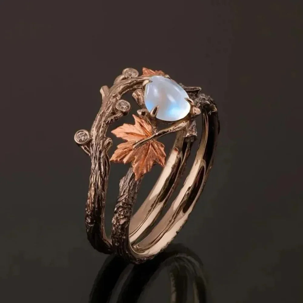 Bague branche d'arbre avec sa pierre blanches, ornée d'une pierre bleue et de délicates feuilles en métal.