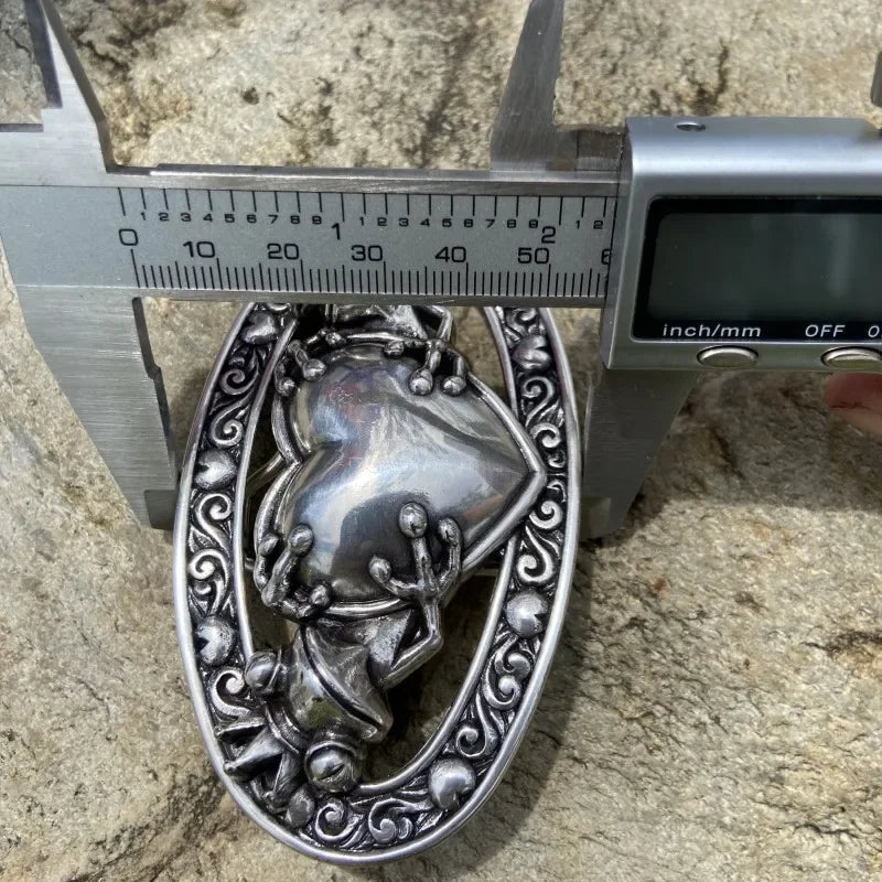 Boucle de ceinture celtique grenouille mesurée avec un pied à coulisse sur une surface texturée.