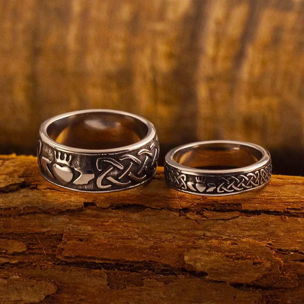 Bague Claddagh en acier inoxydable, modèle homme et modèle femme, sur un fond en bois rustique.