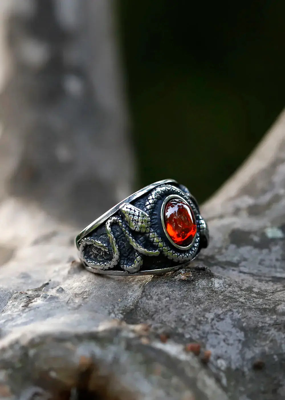 bague du sorcier en acier titane ornée d'un zirconium rouge sur un fond naturel