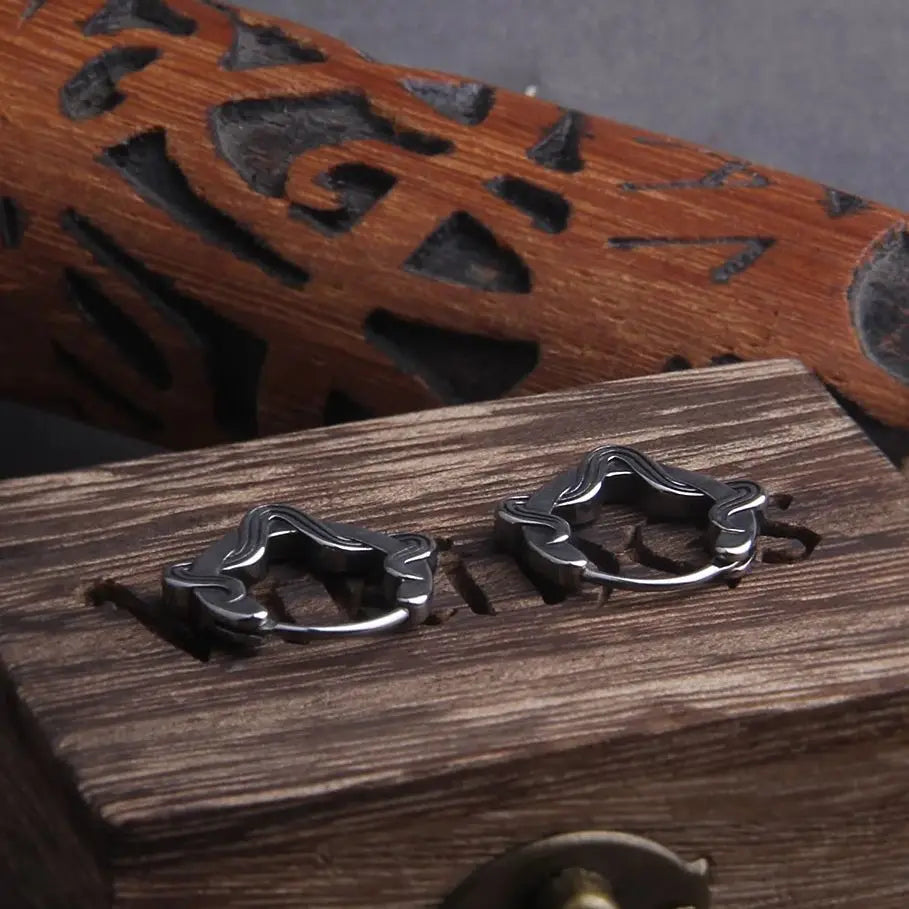 Boucles d'oreilles lacet créoles en acier inoxydable, présentées sur une boîte en bois avec motifs.
