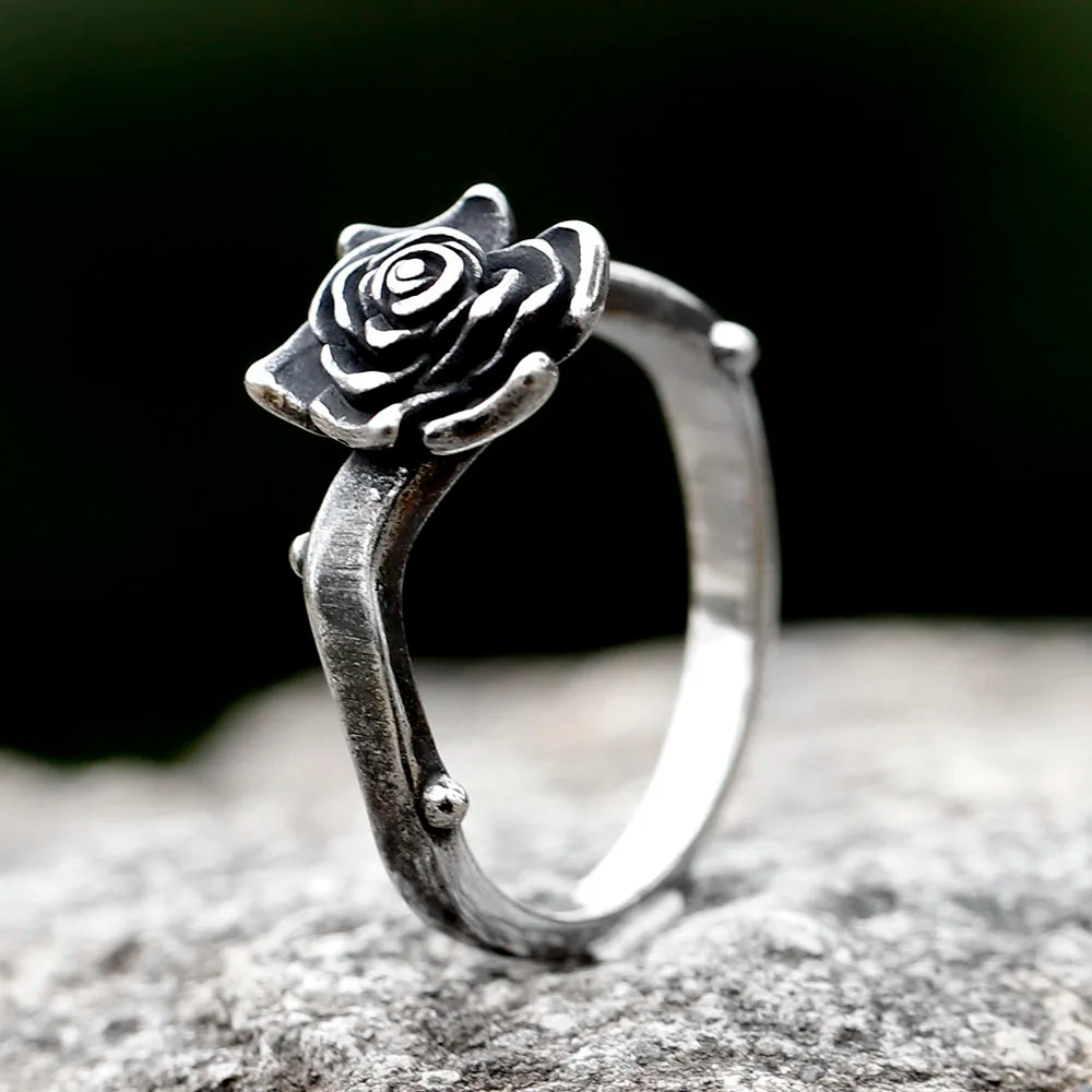 Bague La rose solitaire en acier titane avec motif de rose délicate sur fond flou.