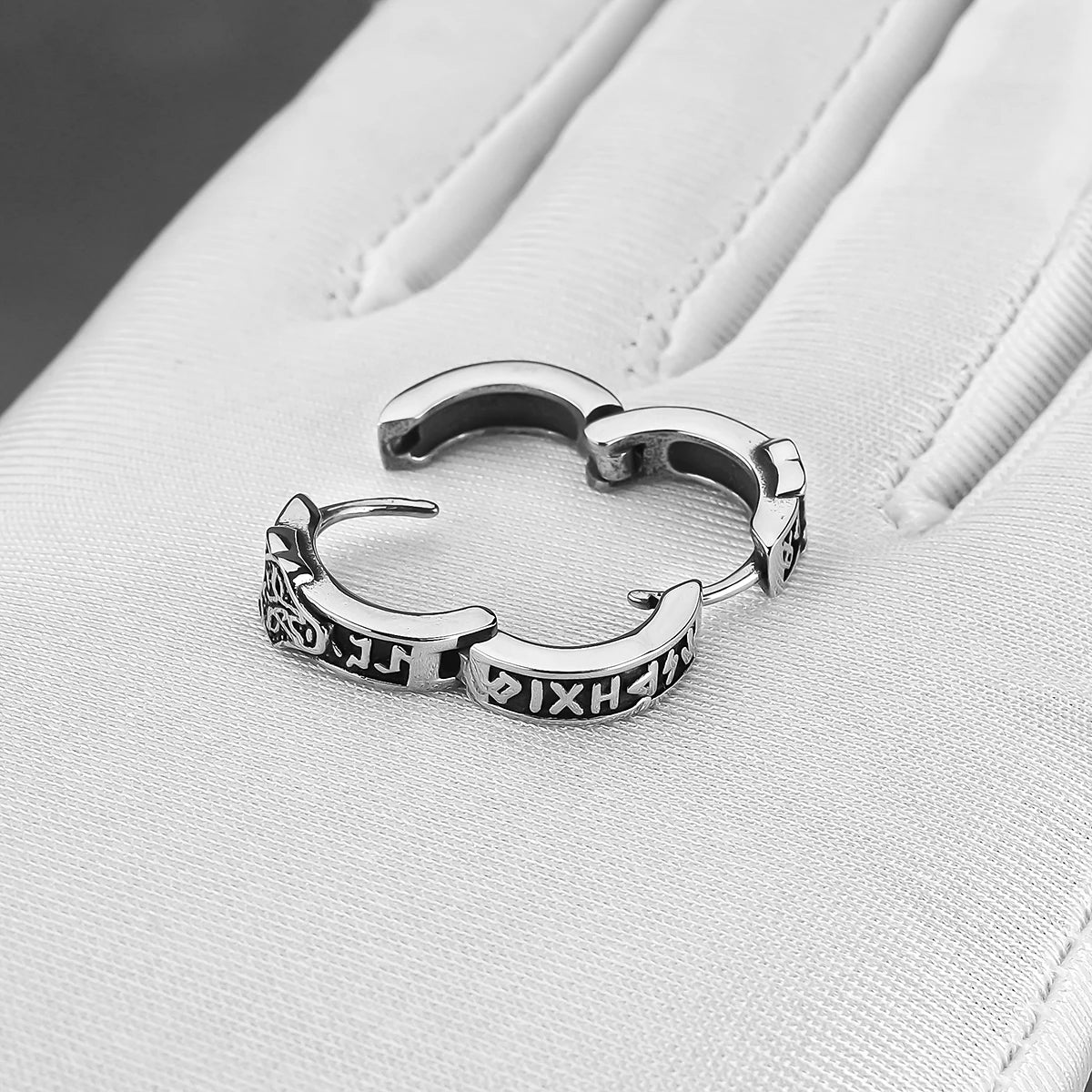 Boucle d'oreille créole tête loup en acier inoxydable sur une main avec un fond blanc.