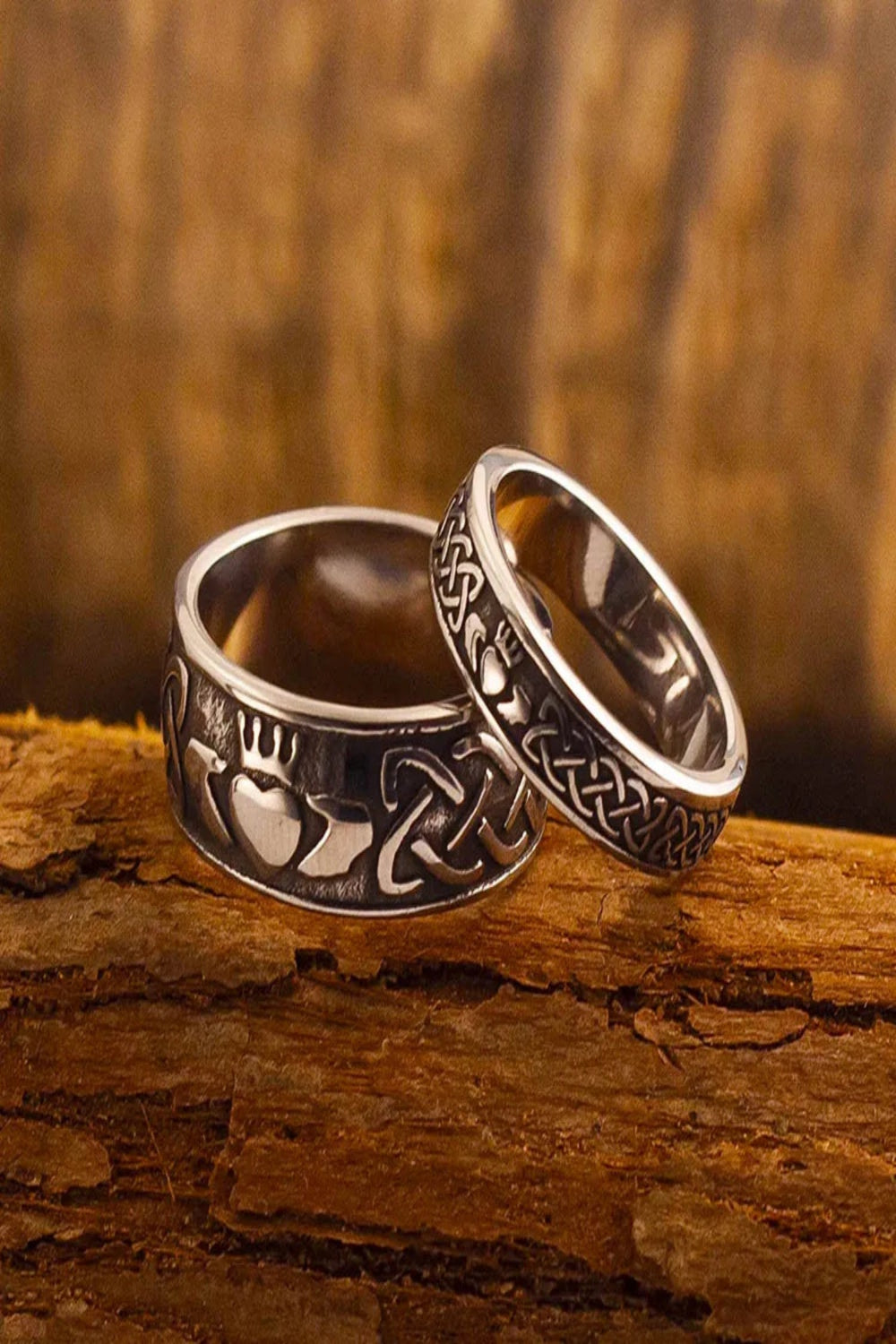 Deux anneaux Claddagh en acier inoxydable, symbolisant l'amour et l'engagement, sur un fond en bois.