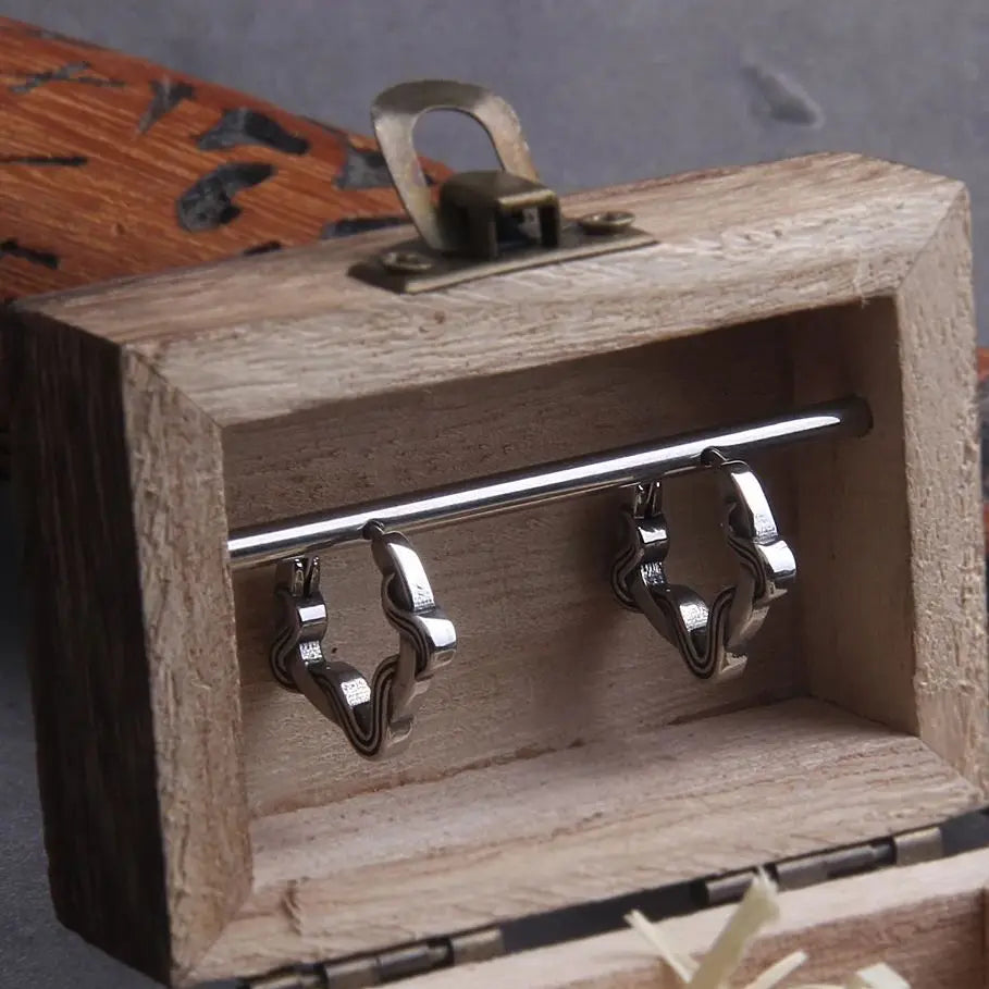 Boucles d'oreilles lacet en acier inoxydable, présentées dans une boîte en bois élégante.